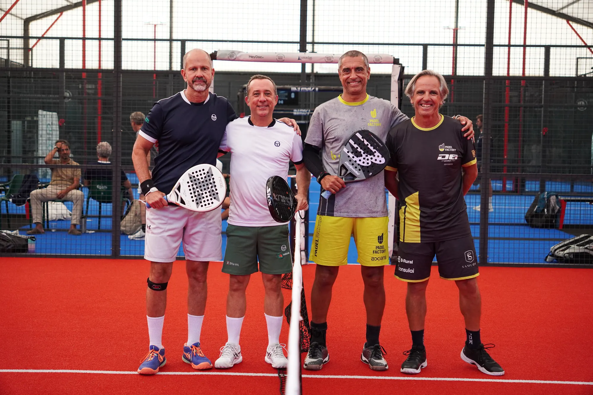 Quatro jogadores de padel posam junto à rede antes de um jogo de veteranos por equipas